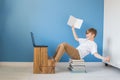 Happy child boy sitting on stack of books with his laptop, studying online at home, modern interior with blue wall background Royalty Free Stock Photo