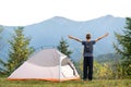 Happy child boy standing with raised hands near a tourist tent at mountain campsite enjoying view of beautiful summer nature. Royalty Free Stock Photo