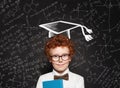 Happy child boy wearing graduation hat on blackboard background with science and maths formulas Royalty Free Stock Photo