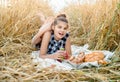 Happy child with bread in yellow autumn wheat field. A field with mature ears.girl sits on a bedspread, fresh fruits and berries, Royalty Free Stock Photo