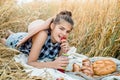 Happy child with bread in yellow autumn wheat field. A field with mature ears.girl sits on a bedspread, fresh fruits and Royalty Free Stock Photo