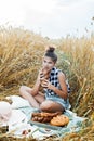 Happy child with bread in yellow autumn wheat field. A field with mature ears.girl sits on a bedspread, fresh fruits and Royalty Free Stock Photo