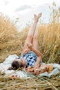 Happy child with bread in yellow autumn wheat field. A field with mature ears.girl sits on a bedspread, fresh fruits and Royalty Free Stock Photo