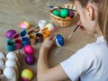 Happy child celebrates easter. A girl in a white T-shirt paints Easter colored eggs with paints and a brush close-up. Royalty Free Stock Photo