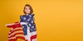 Happy child, cute girl with American flag on yellow studio background. USA celebrate July 4th, independence Day.