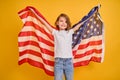 Happy child, cute girl with American flag on yellow studio background. USA celebrate July 4th, independence Day.