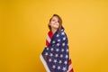 Happy child, cute girl with American flag on yellow studio background. USA celebrate July 4th, independence Day.