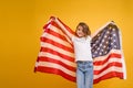 Happy child, cute girl with American flag on yellow studio background. USA celebrate July 4th, independence Day.