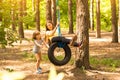 Happy child daughter pushing mother on tire swing in garden Royalty Free Stock Photo