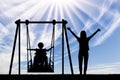 Happy child is disabled in a wheelchair on an adaptive swing for disabled children with mom