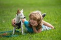 Happy child and dog hugs, lying on backyard lawn. Cute boy child with dog relaxing on park. Puppies and child in grass Royalty Free Stock Photo