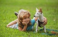 Happy child and dog hugs, lying on backyard lawn. Cute boy child with dog relaxing on park. Puppies and child in grass Royalty Free Stock Photo