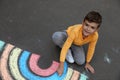 Happy child drawing rainbow with chalk on asphalt, above view Royalty Free Stock Photo