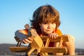 Happy child dreams of traveling and playing with toy airplane. Little pilot aviator in outdoor against blue summer sky Royalty Free Stock Photo