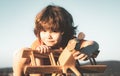 Happy child dreams of traveling and playing with toy airplane. Little pilot aviator in outdoor against blue summer sky Royalty Free Stock Photo