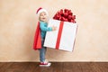 Happy child dressed superhero holding Christmas gift box Royalty Free Stock Photo