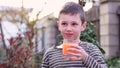 Happy child drinks ffresh grapefruit juice with ice cubes from a glass in outdoor. Healthy and proper nutrition of