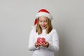 Happy child enjoying Christmas gift. Young girl in Santa hat with red Xmas present box on white background Royalty Free Stock Photo