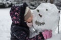 Child kissing a cold snowman in winter time Royalty Free Stock Photo