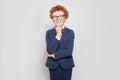 Happy child with ginger hair portrait. Little boy in blue suit standing against white wall background