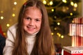 Happy child girl on background of Christmas tree and glittering lights near gifts Royalty Free Stock Photo