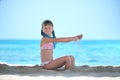 Happy child girl in bikini swimsuit playing with sand on seaside beach during summer tropical vacation Royalty Free Stock Photo