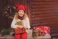 Happy child girl celebrating christmas outdoor at cozy wooden country house