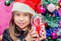 Happy child girl in a Christmas hat holding glass globe gift of