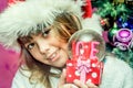 Happy child girl in a Christmas hat holding glass globe gift of