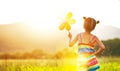 Happy child girl with colorful pinwheel windmill in summer