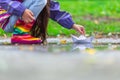 Happy child girl with colorful rubber boots playing with paper boat in puddle in autumn on nature Royalty Free Stock Photo