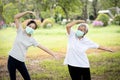 Happy child girl is doing exercise activity for the old elderly,healthy senior woman workout and wear face mask outside home after