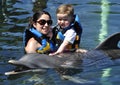 Child and girl with dolphin in blue water. Royalty Free Stock Photo