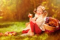 Happy child girl eating apples in autumn sunny garden