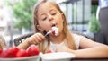 happy child girl eats strawberries in the summer,Young cute smiling european little girl is eating ripe jucy strawberry with sour Royalty Free Stock Photo