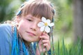 Happy child girl enjoying sweet smell of white narcissus flowers in summer garden