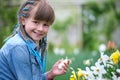 Happy child girl enjoying sweet smell of white narcissus flowers in summer garden
