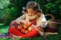 Happy child girl harvesting apples in autumn garden.