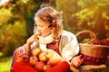 Happy child girl harvesting apples in autumn garden.