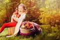 Happy child girl harvesting apples in autumn garden.