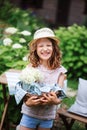 Happy child girl in hat enjoying warm summer day in the blooming garden Royalty Free Stock Photo