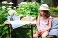 Happy child girl in hat enjoying warm summer day in the blooming garden Royalty Free Stock Photo