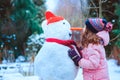 happy child girl having fun and building snowman on winter walk in snowy garden Royalty Free Stock Photo