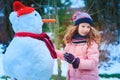 happy child girl having fun and building snowman on winter walk in snowy garden Royalty Free Stock Photo