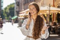 Happy child girl having remote conversation talking on smartphone, good news gossip in city street Royalty Free Stock Photo