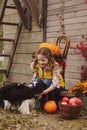 Happy child girl and her dog picking fresh apples on the farm. Country living concept