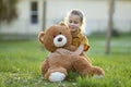 Happy child girl hugging her teddy bear friend outdoors on green grass lawn. Friendship concept Royalty Free Stock Photo