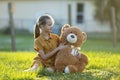 Happy child girl hugging her teddy bear friend outdoors on green grass lawn. Friendship concept Royalty Free Stock Photo