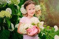 Happy child girl with hydrangea bouquet playing outdoor in cozy summer garden