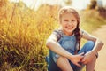 Happy child girl in jeans overall playing on sunny field, summer outdoor lifestyle